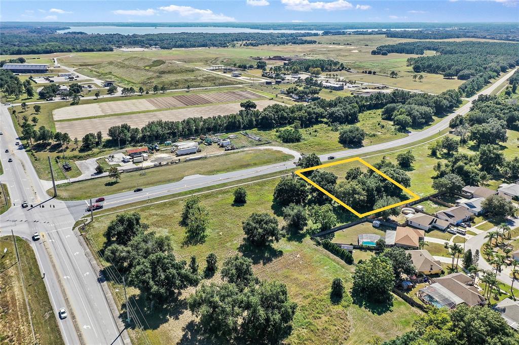 An aerial view shows a wooded, rectangular plot of land outlined in yellow near a road — CR-448 Lot 2, TAVARES, FL