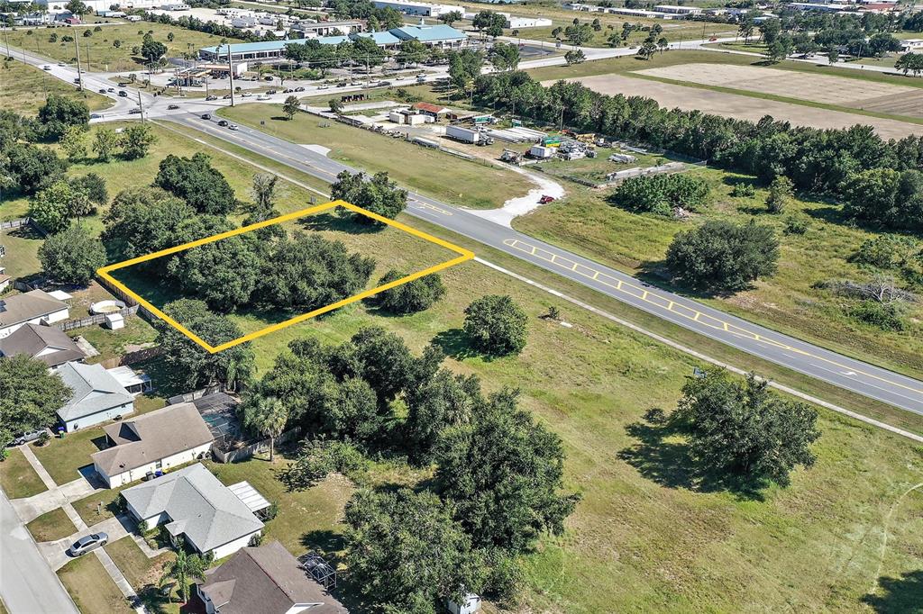 An aerial view shows a rectangular vacant lot outlined in yellow next to a road — CR-448 Lot 2, TAVARES, FL