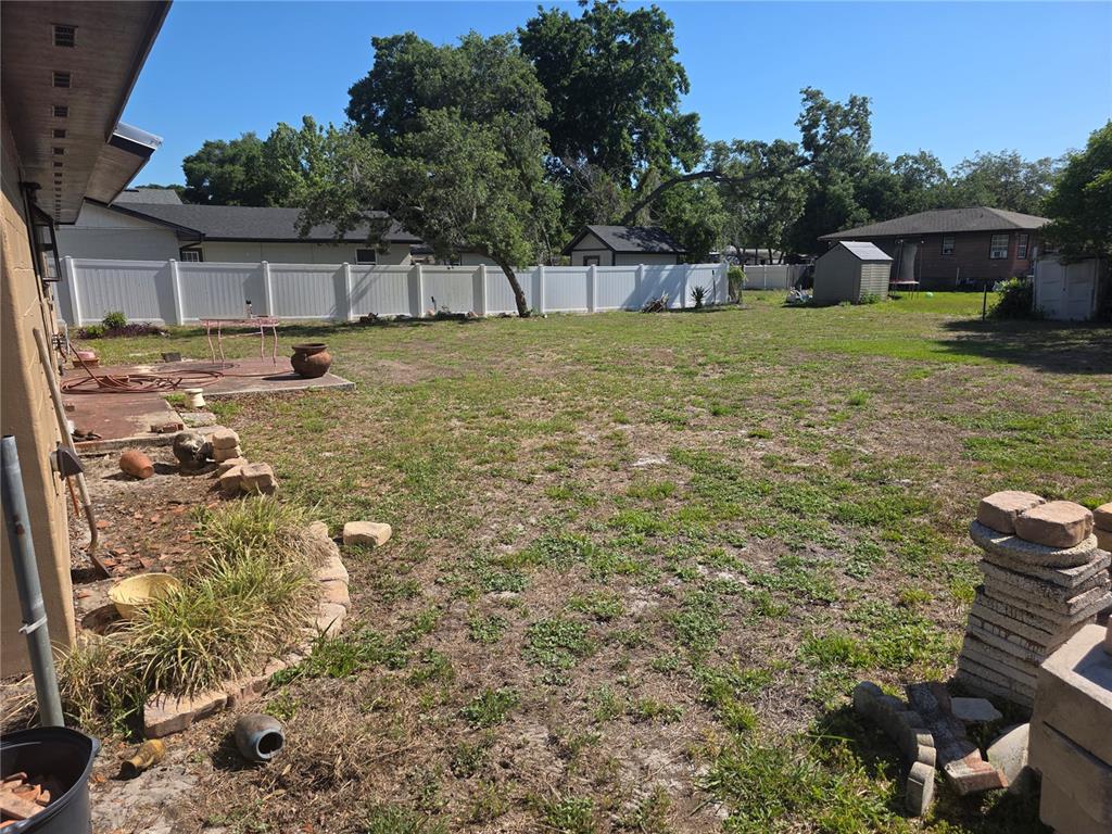 A large, grassy backyard features a white vinyl fence, a shed, and a concrete patio — 9387 JUNIOR AVENUE, APOPKA, FL