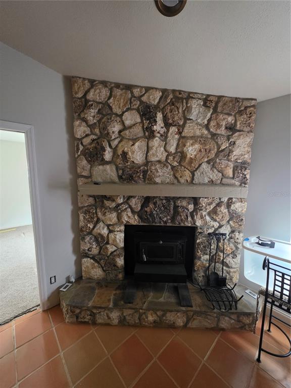 A stone fireplace with a wood-burning insert and a raised hearth sits in a room — 9387 JUNIOR AVENUE, APOPKA, FL