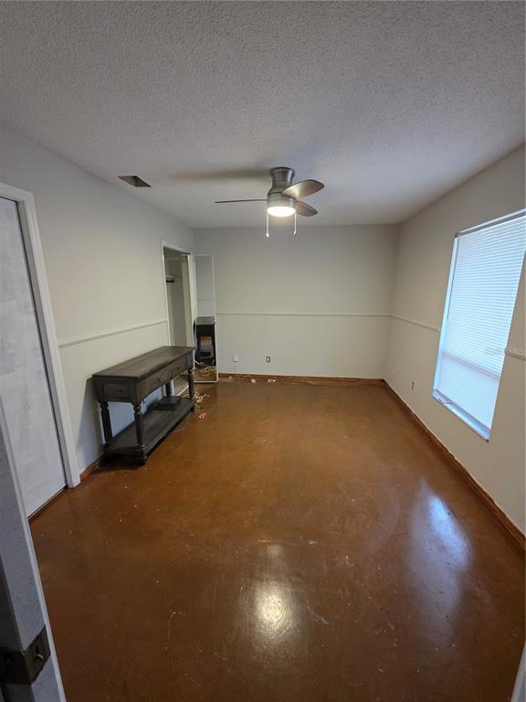 An empty bedroom with a ceiling fan, chair rail molding, and stained concrete flooring — 9387 JUNIOR AVENUE, APOPKA, FL