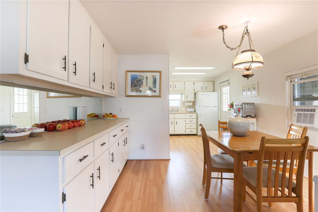 A kitchen and dining area feature white cabinets, light wood flooring, and a wooden table — 2100 KINGS HIGHWAY UNIT 539, PORT CHARLOTTE, FL