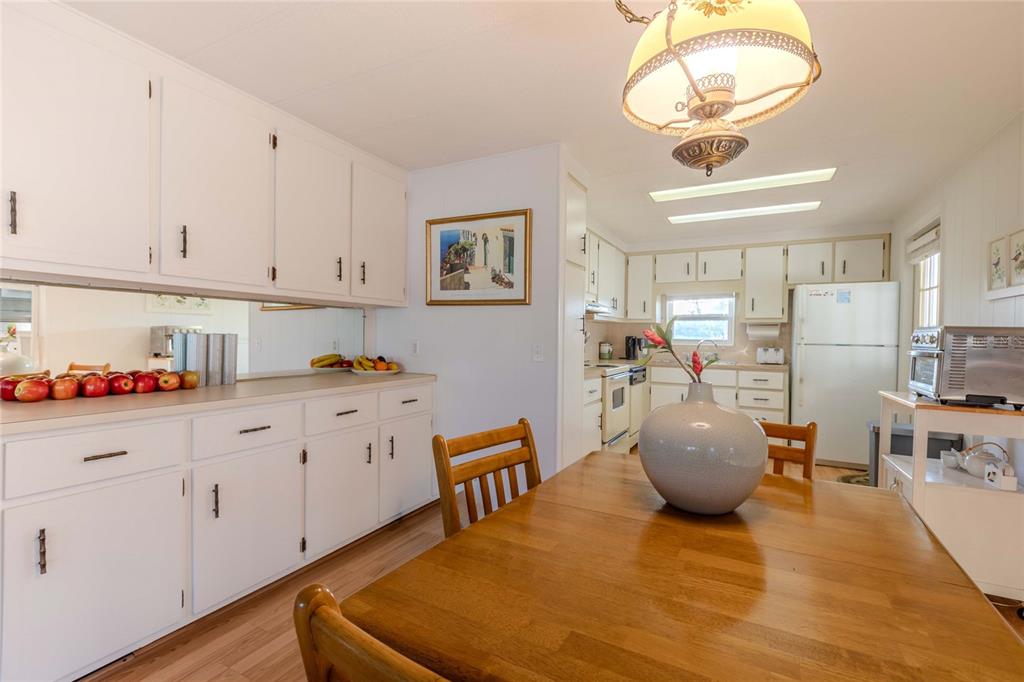 A kitchen with white cabinets, a wooden dining table, and a large central pendant light — 2100 KINGS HIGHWAY UNIT 539, PORT CHARLOTTE, FL