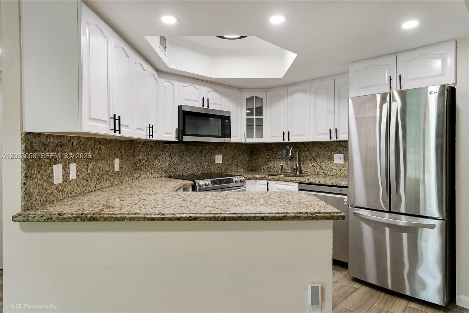 A kitchen features white cabinets, granite countertops, stainless steel appliances, and a recessed ceiling light — 8205 Lake Dr # 103, Doral FL 33166, DORAL, FL
