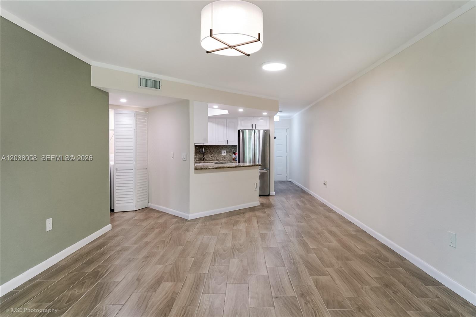 This room features wood-look tile flooring, a green accent wall, and an open kitchen area — 8205 Lake Dr # 103, Doral FL 33166, DORAL, FL