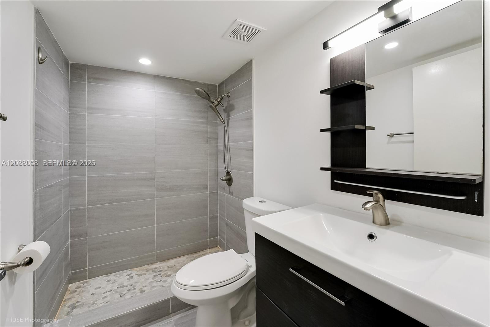 A modern bathroom features a tiled walk-in shower, a toilet, and a dark wood vanity — 8205 Lake Dr # 103, Doral FL 33166, DORAL, FL