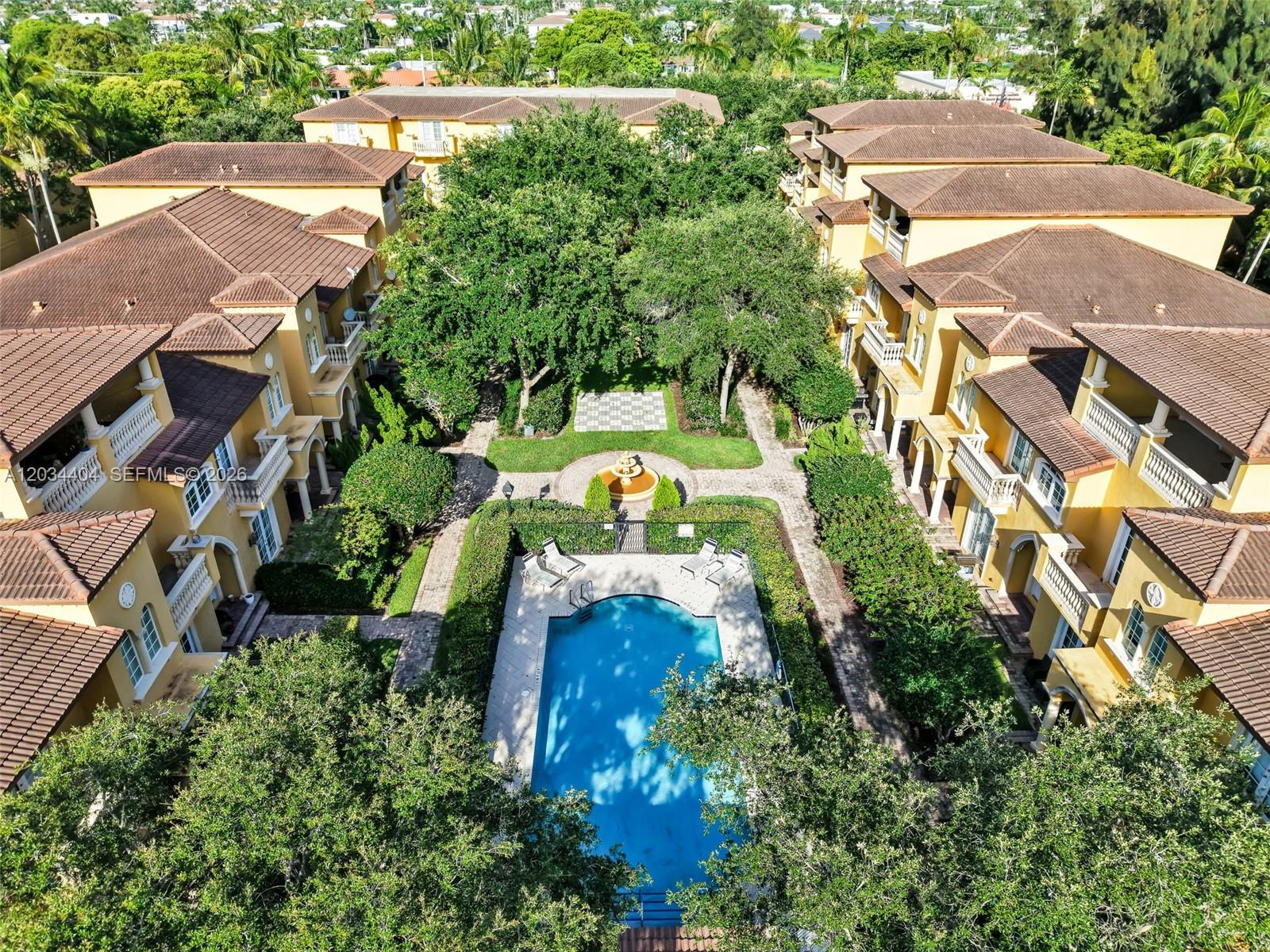 An aerial view shows a swimming pool and courtyard surrounded by multi-story yellow apartment buildings — 425 NE 69th Cir, Boca Raton FL 33487, BOCA RATON, FL
