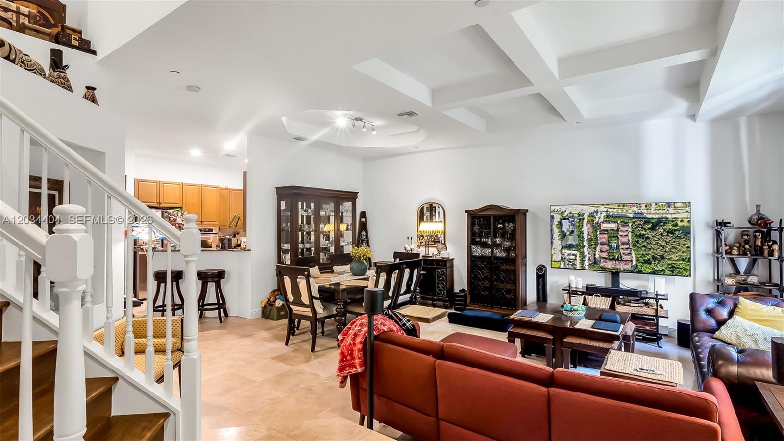 An open-concept living and dining area features tile flooring, coffered ceilings, and a red sofa — 425 NE 69th Cir, Boca Raton FL 33487, BOCA RATON, FL