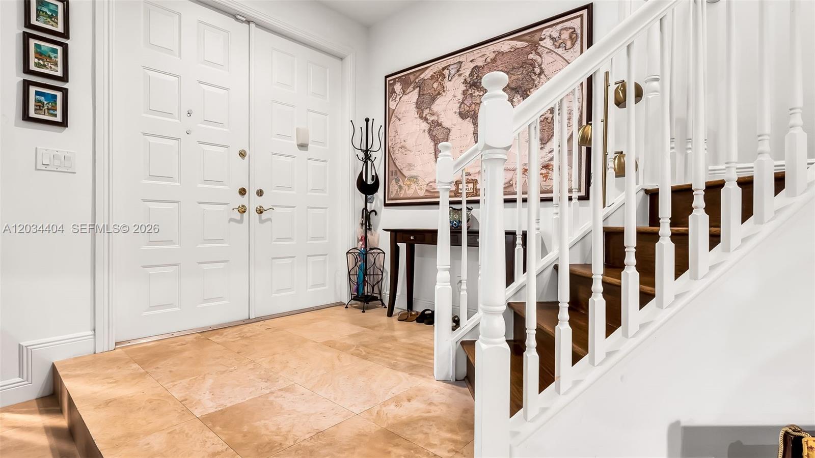 An entryway features a double door, a staircase with white railings, and a world map — 425 NE 69th Cir, Boca Raton FL 33487, BOCA RATON, FL