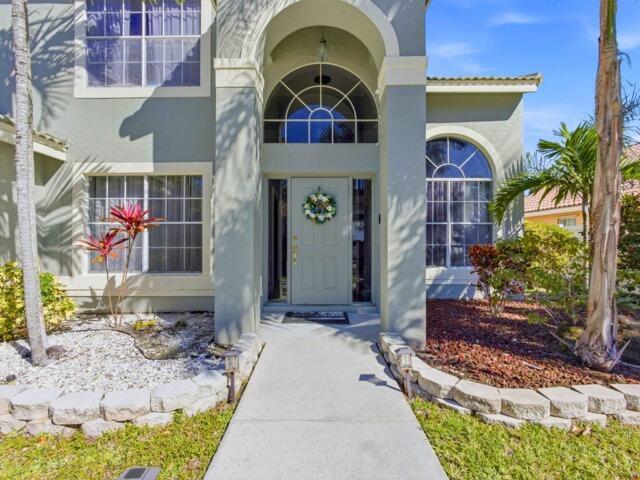 A concrete walkway leads to the front entrance of a two-story house with arched windows — 5528 Descartes Circle, Boynton Beach FL 33472, BOYNTON BEACH, FL