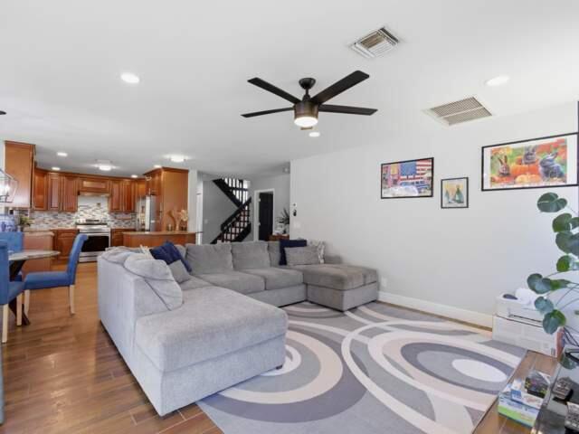 A living room with a gray sectional sofa, patterned rug, and an open-concept kitchen — 5528 Descartes Circle, Boynton Beach FL 33472, BOYNTON BEACH, FL