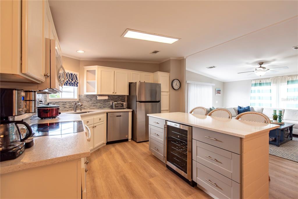 A kitchen with white cabinets, stainless steel appliances, and a central island with a wine cooler — 21 AMSTERDAM AVENUE, PUNTA GORDA, FL
