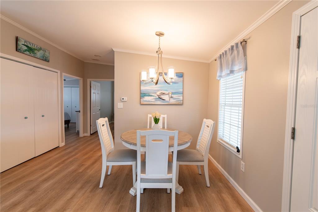 A dining area features a round wooden table, white chairs, and a coastal-themed painting — 21 AMSTERDAM AVENUE, PUNTA GORDA, FL