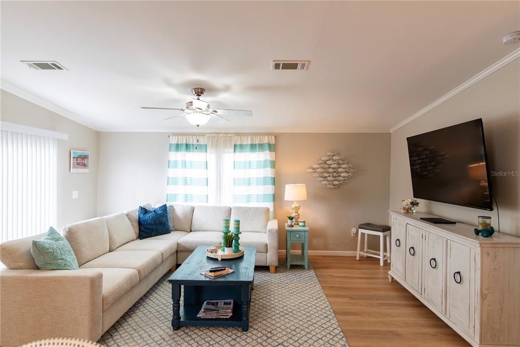 A living room features a beige sectional sofa, a blue coffee table, and a television — 21 AMSTERDAM AVENUE, PUNTA GORDA, FL