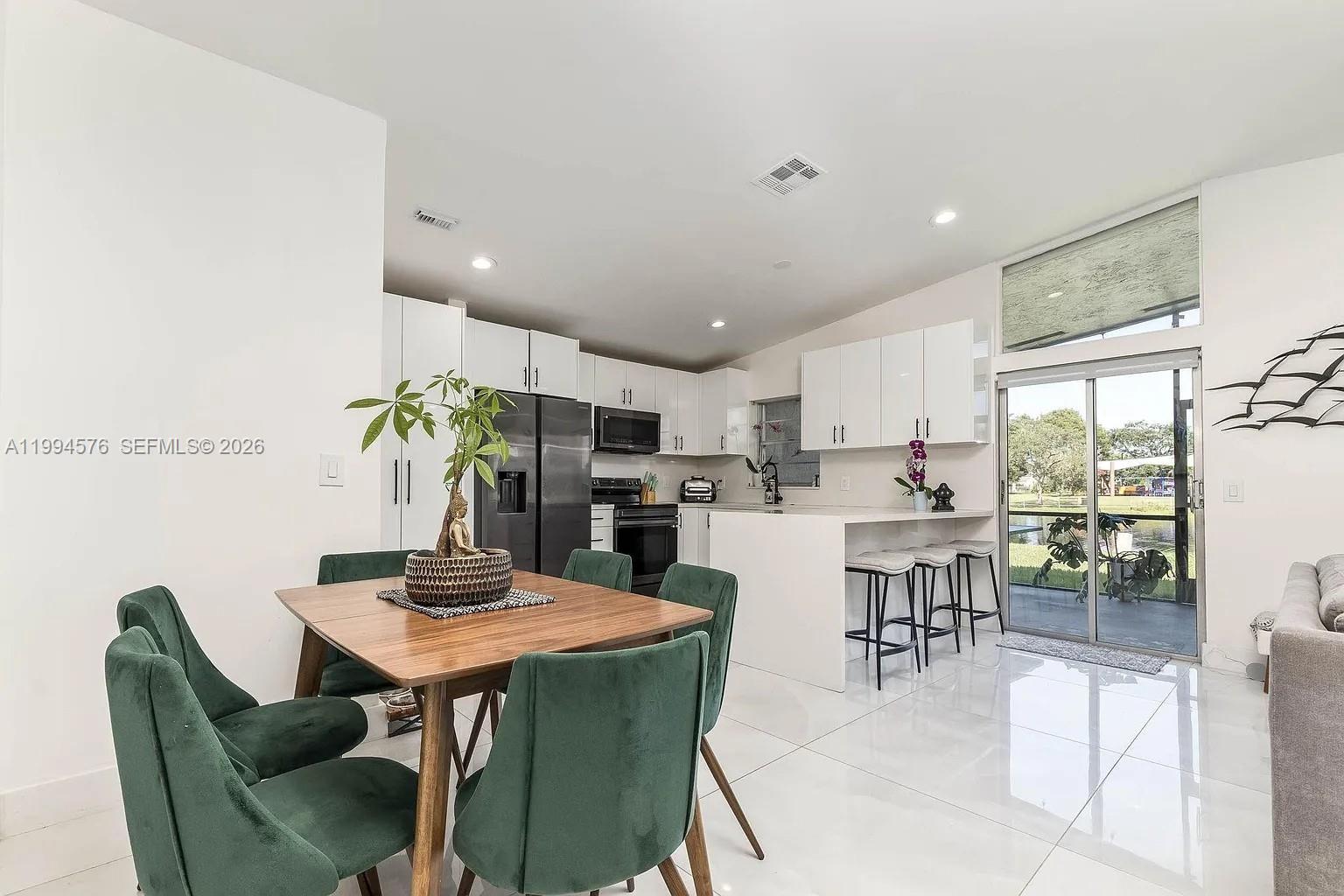 A dining area and kitchen feature white cabinetry, stainless steel appliances, and tile flooring — 518 Woodgate Cir, Sunrise FL 33326, SUNRISE, FL