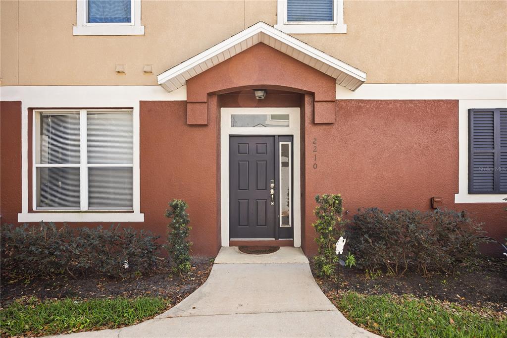A front exterior view of a two-story home with a dark door and walkway — 2210 SAN JACINTO CIRCLE, SANFORD, FL