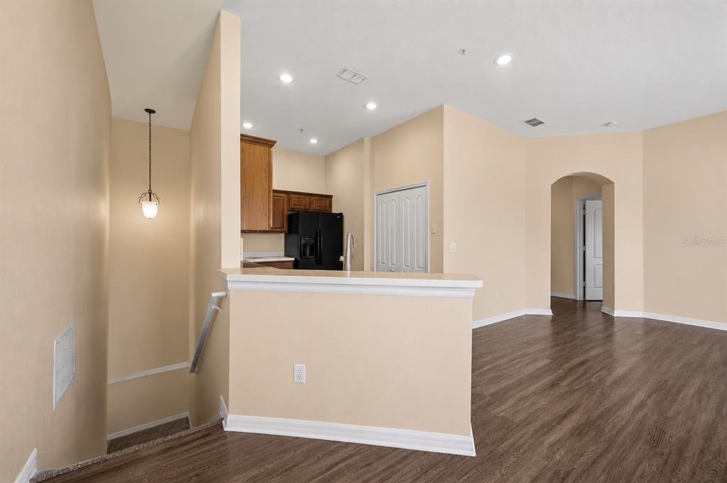 A kitchen with dark wood cabinets and black appliances overlooks a living area with flooring — 2210 SAN JACINTO CIRCLE, SANFORD, FL