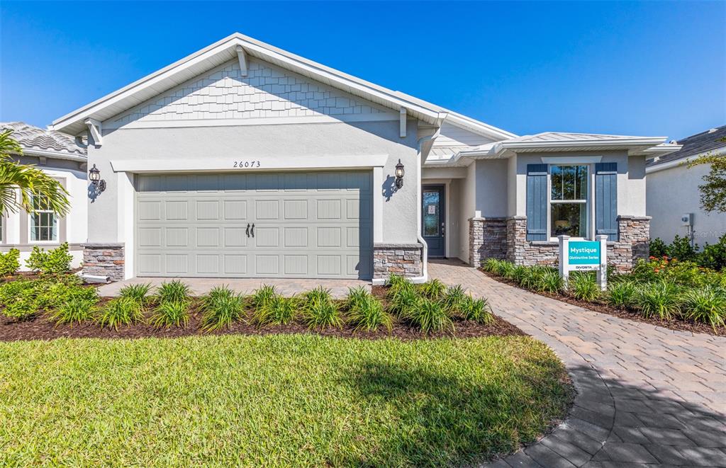 A single-story house features a two-car garage, stone accents, and a paved walkway — 26637 BERING DRIVE, ENGLEWOOD, FL