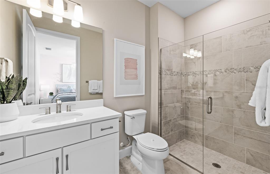 A bathroom features a white vanity, a toilet, and a glass-enclosed tiled walk-in shower — 26637 BERING DRIVE, ENGLEWOOD, FL
