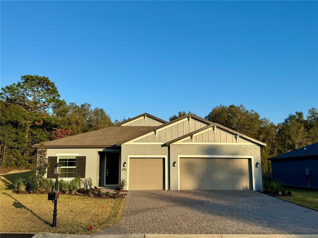 A single-story house with a gray stucco exterior, two garage doors, and a paved driveway — 6606 SW 180TH CIRCLE, DUNNELLON, FL