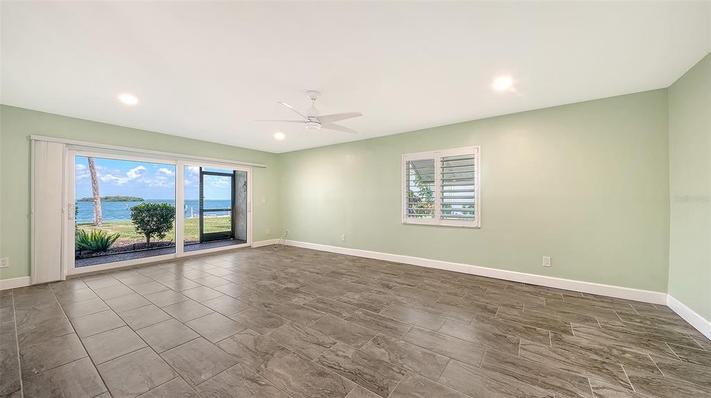 A spacious room with light green walls, gray tile flooring, and a large waterfront view — 4234 GULF OF MEXICO DRIVE UNIT M1, LONGBOAT KEY, FL