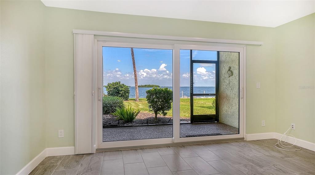 A room with light green walls and tile flooring features a large sliding glass door — 4234 GULF OF MEXICO DRIVE UNIT M1, LONGBOAT KEY, FL