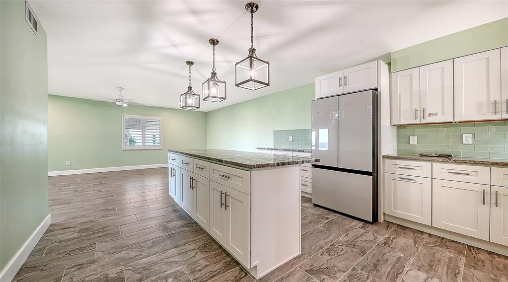 A kitchen with white cabinets, a granite island, stainless steel appliances, and light green walls — 4234 GULF OF MEXICO DRIVE UNIT M1, LONGBOAT KEY, FL