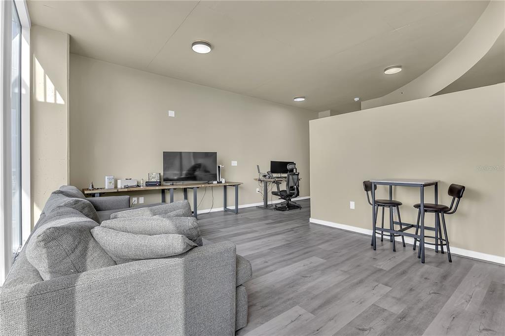 A living area features gray wood-look flooring, a gray sofa, a desk, and a small table — 155 S COURT AVENUE UNIT 1506, ORLANDO, FL