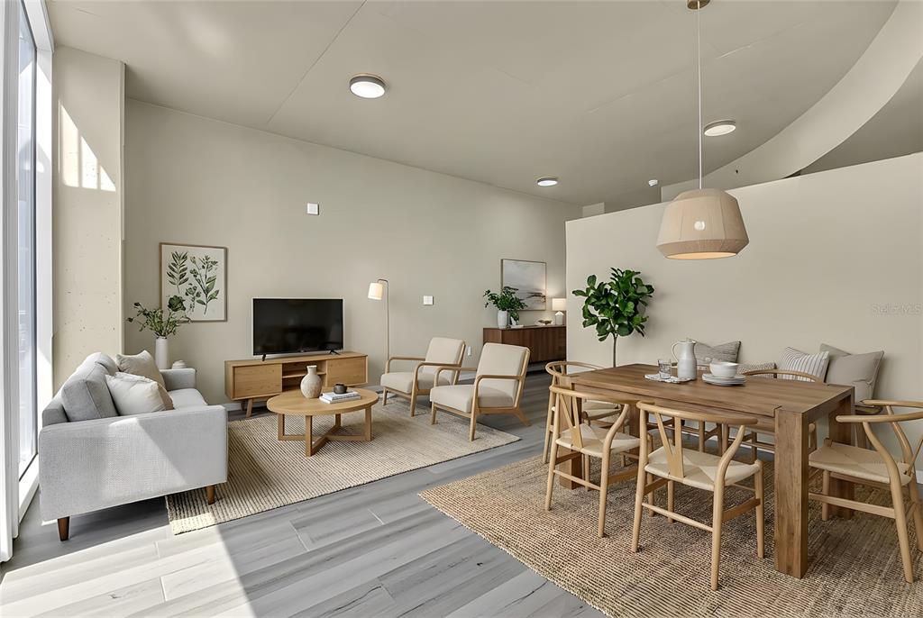 An open-concept living and dining area features light wood furniture, neutral decor, and gray flooring — 155 S COURT AVENUE UNIT 1506, ORLANDO, FL