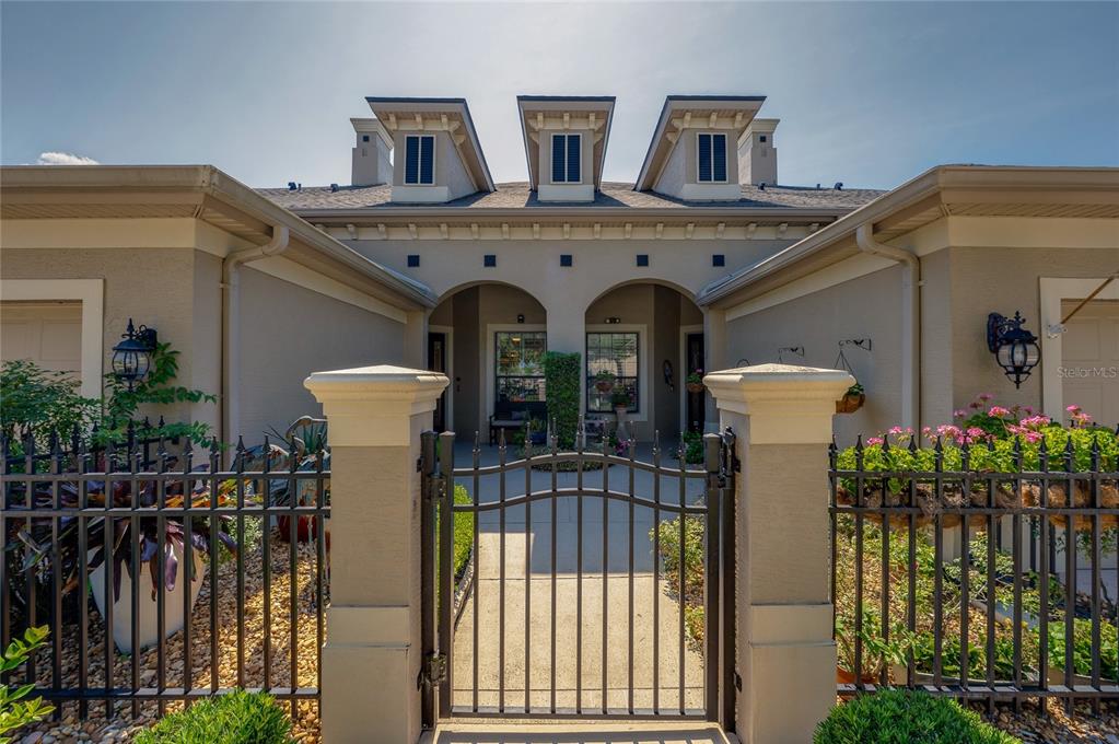 A gated courtyard leads to the front entrance of a house with three roof dormers — 735 COBBLESTONE DRIVE, ORMOND BEACH, FL