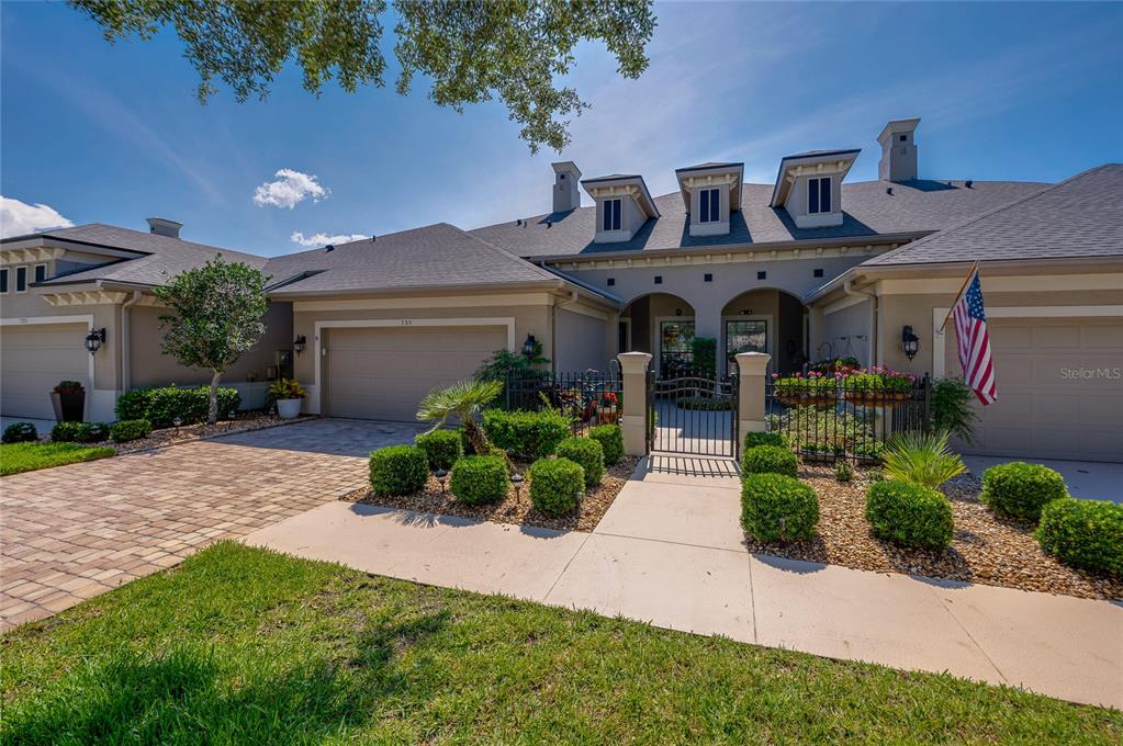 A single-story house exterior with a paved driveway, gated courtyard, and attached garages — 735 COBBLESTONE DRIVE, ORMOND BEACH, FL