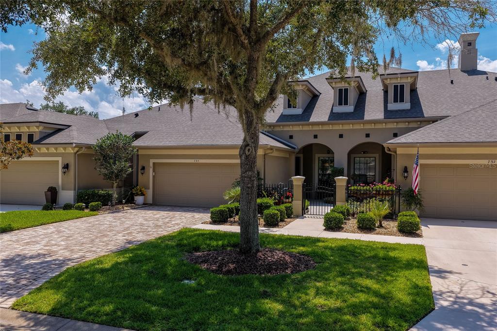 A multi-unit residential building features beige stucco walls, arched entryways, and a paved driveway — 735 COBBLESTONE DRIVE, ORMOND BEACH, FL