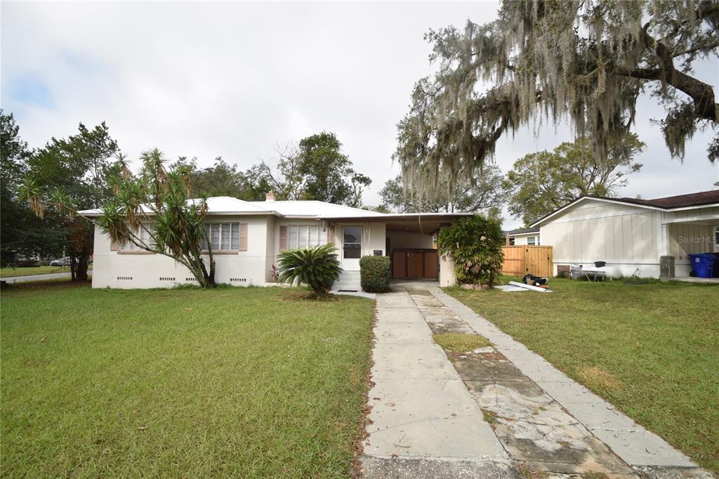 A single-story house with a white exterior, a carport, and a concrete driveway — 3115 BUCKINGHAM AVENUE, LAKELAND, FL