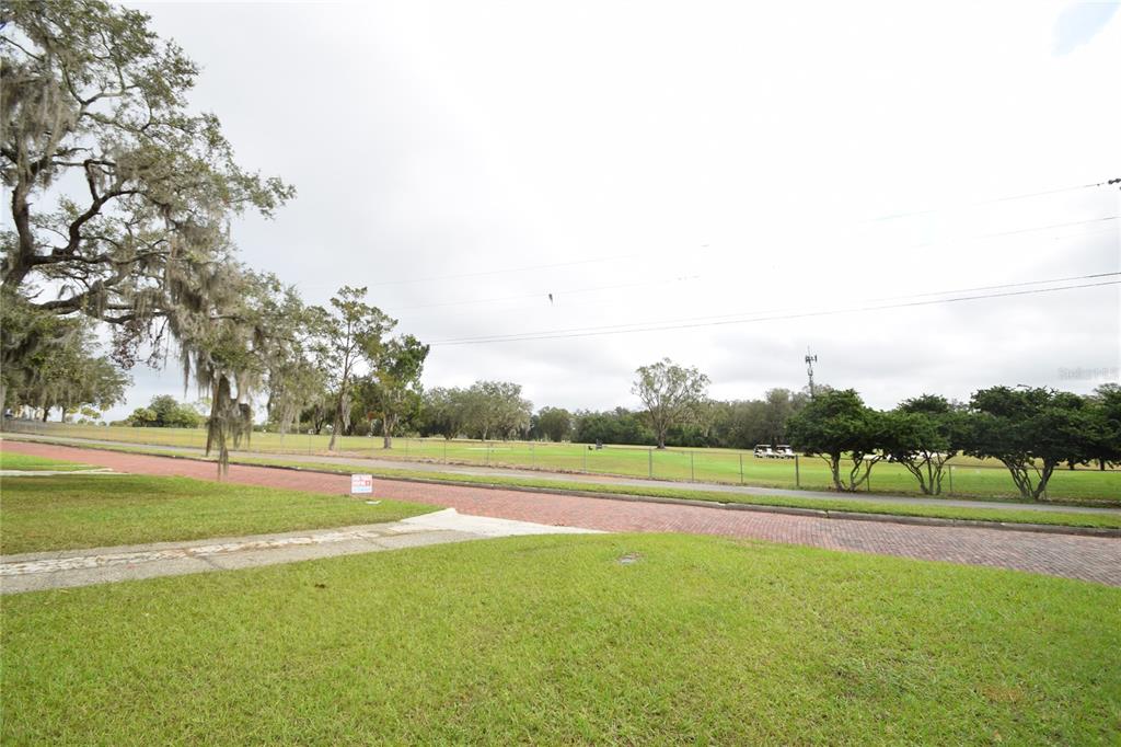 A grassy lot overlooks a brick street and a golf course with scattered trees — 3115 BUCKINGHAM AVENUE, LAKELAND, FL