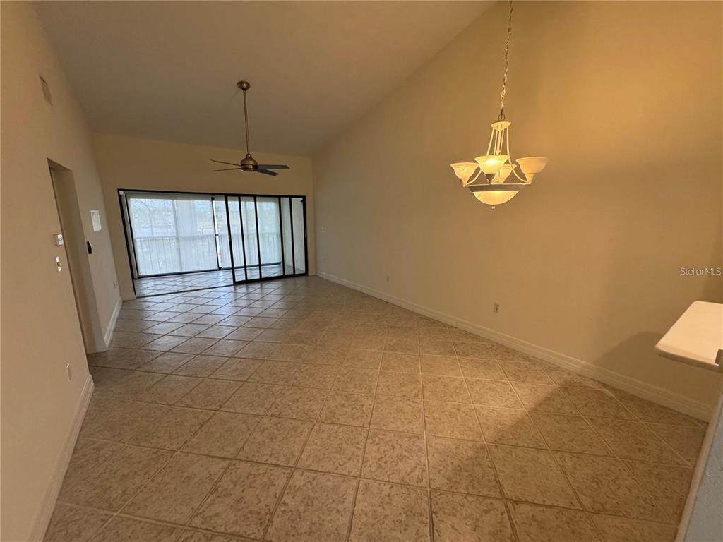 A dining area with tile flooring, a chandelier, and sliding glass doors to a balcony — 2275 S MCCALL ROAD UNIT 201, ENGLEWOOD, FL