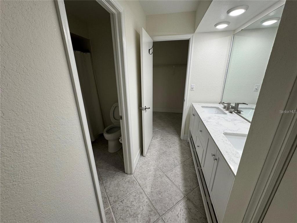 A bathroom features a double vanity with a marble countertop and an adjacent walk-in closet — 2275 S MCCALL ROAD UNIT 201, ENGLEWOOD, FL