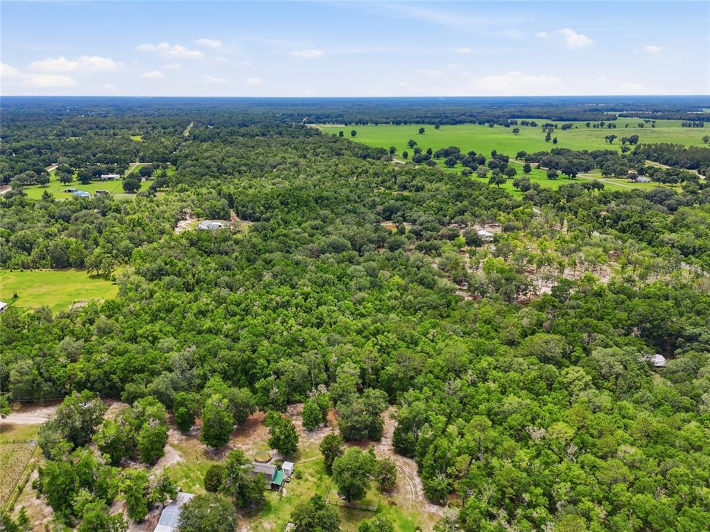 An aerial view shows a large, wooded property with scattered houses and open pasture land — 00 SW SQUIRREL COURT, FORT WHITE, FL