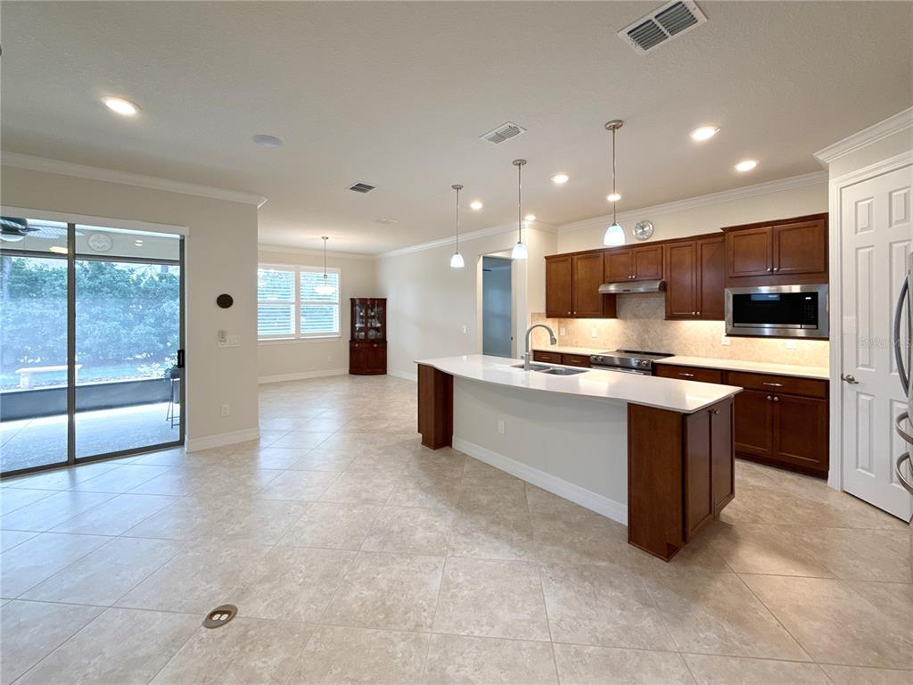 A kitchen with dark wood cabinets, a white island, and tile flooring opens to a patio — 7559 SW 97TH AVENUE, OCALA, FL