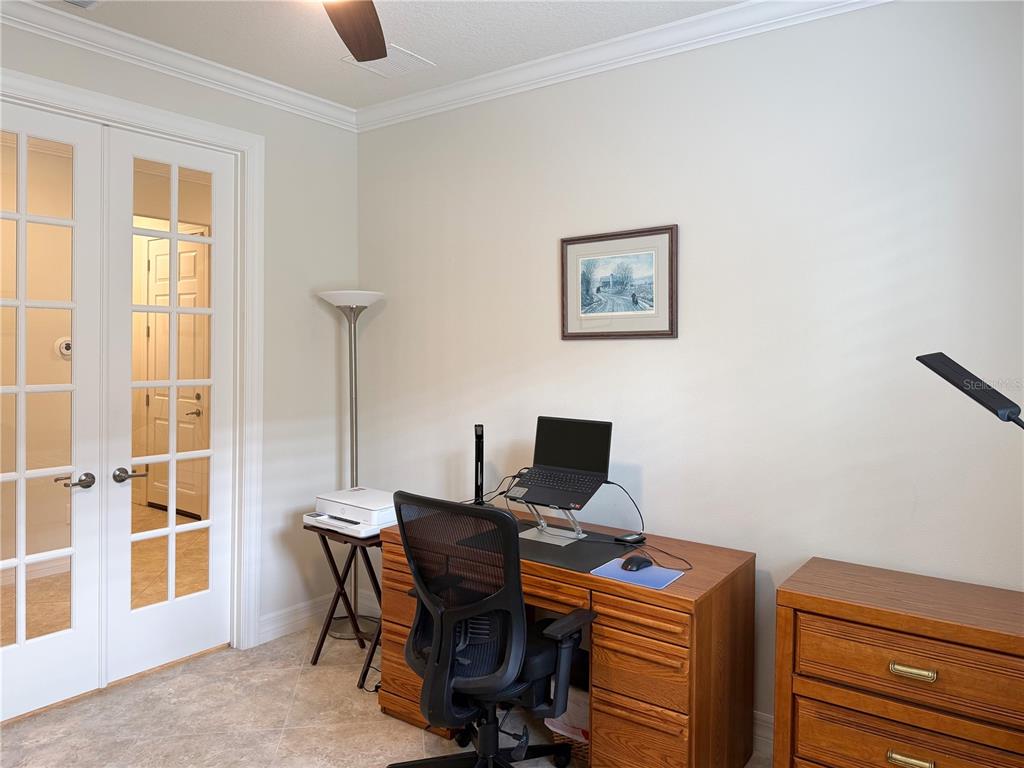 A home office features a wooden desk, a black mesh chair, and French doors — 7559 SW 97TH AVENUE, OCALA, FL
