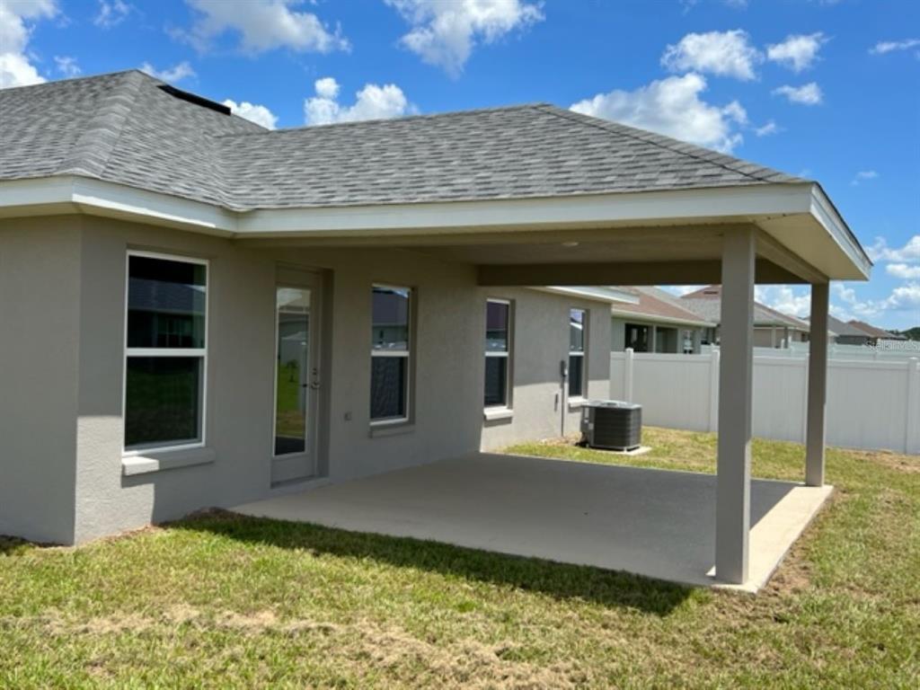 A covered concrete patio extends from the rear of a house with a gray exterior — 2206 NW 23RD LOOP, OCALA, FL