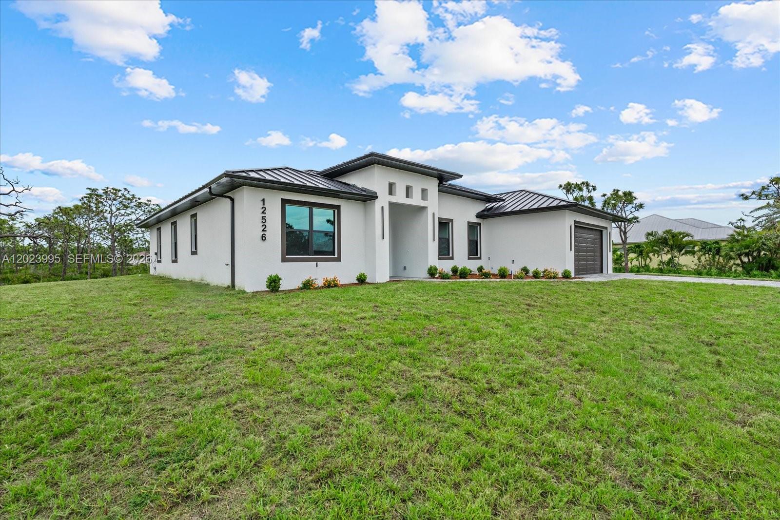 A modern single-story house with a white stucco exterior and a dark metal roof — 12526 Indian Shell Trail, Bokeelia FL 33922, BOKEELIA, FL