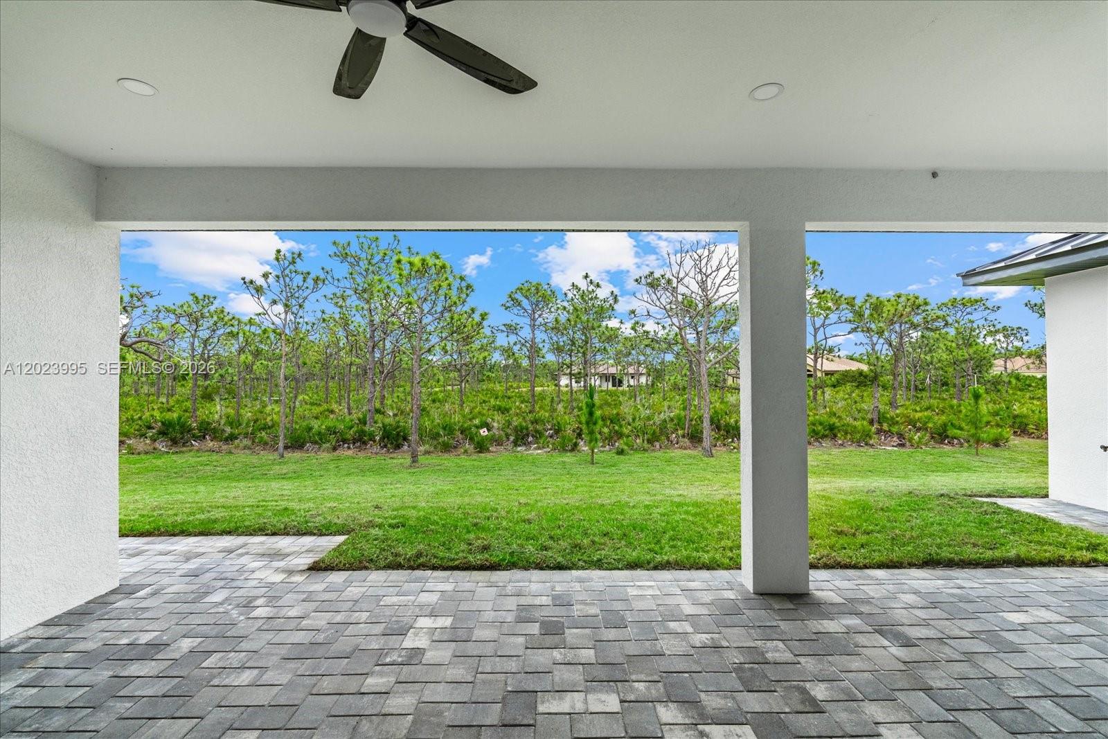 A covered patio with a ceiling fan overlooks a grassy yard and a wooded area — 12526 Indian Shell Trail, Bokeelia FL 33922, BOKEELIA, FL