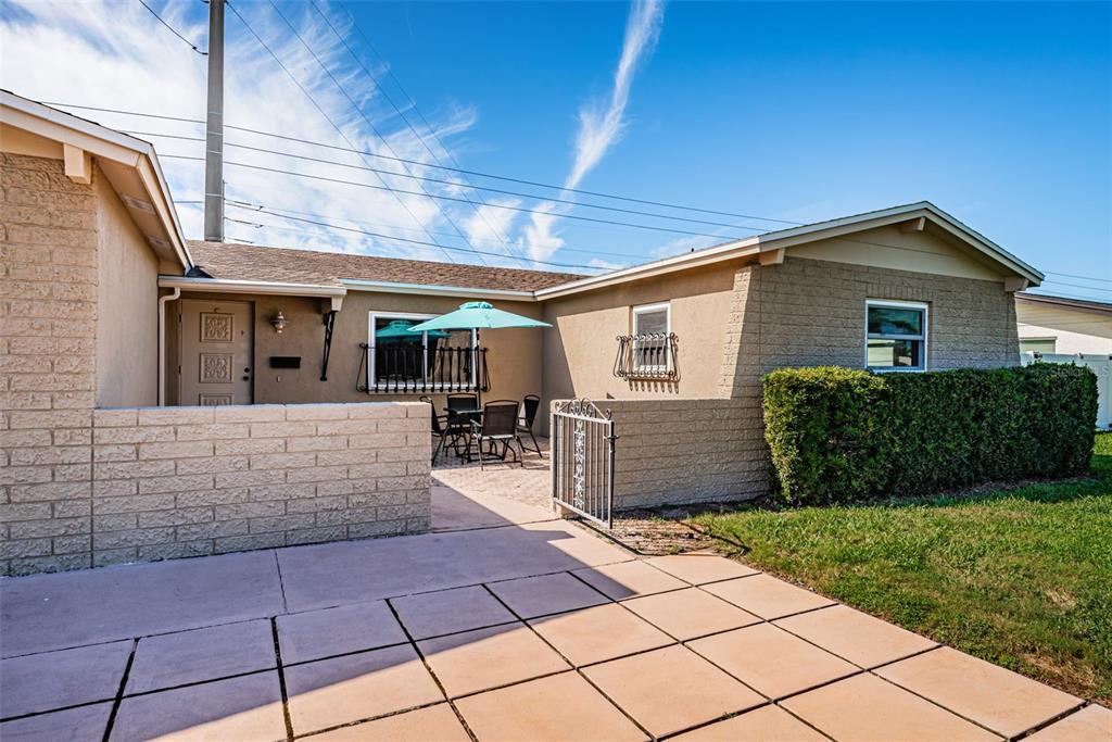 A paved patio area features a small dining set under an umbrella and a gate — 4106 53RD AVENUE S, ST PETERSBURG, FL