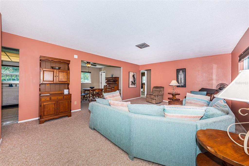 A living room with coral walls, beige carpeting, and a large blue sectional sofa — 4106 53RD AVENUE S, ST PETERSBURG, FL