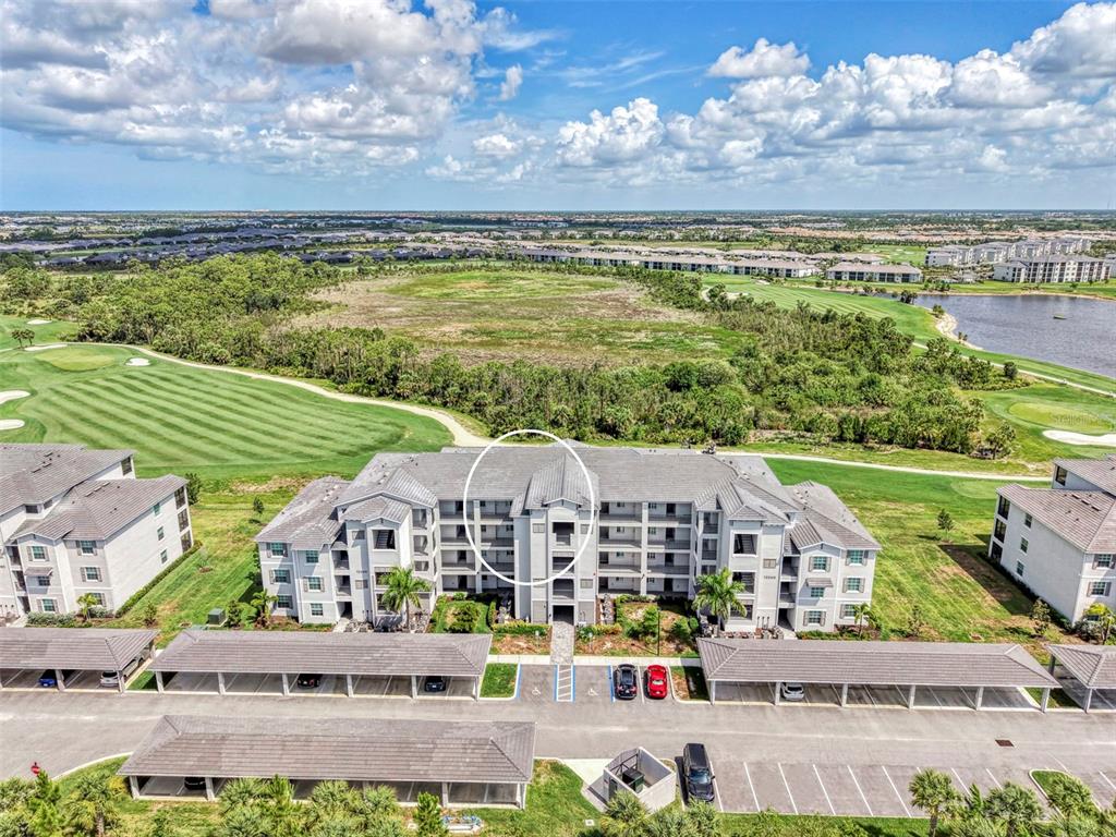An aerial view shows a multi-story apartment building with covered parking and a golf course — 12240 WELLEN GOLF STREET UNIT 304, VENICE, FL