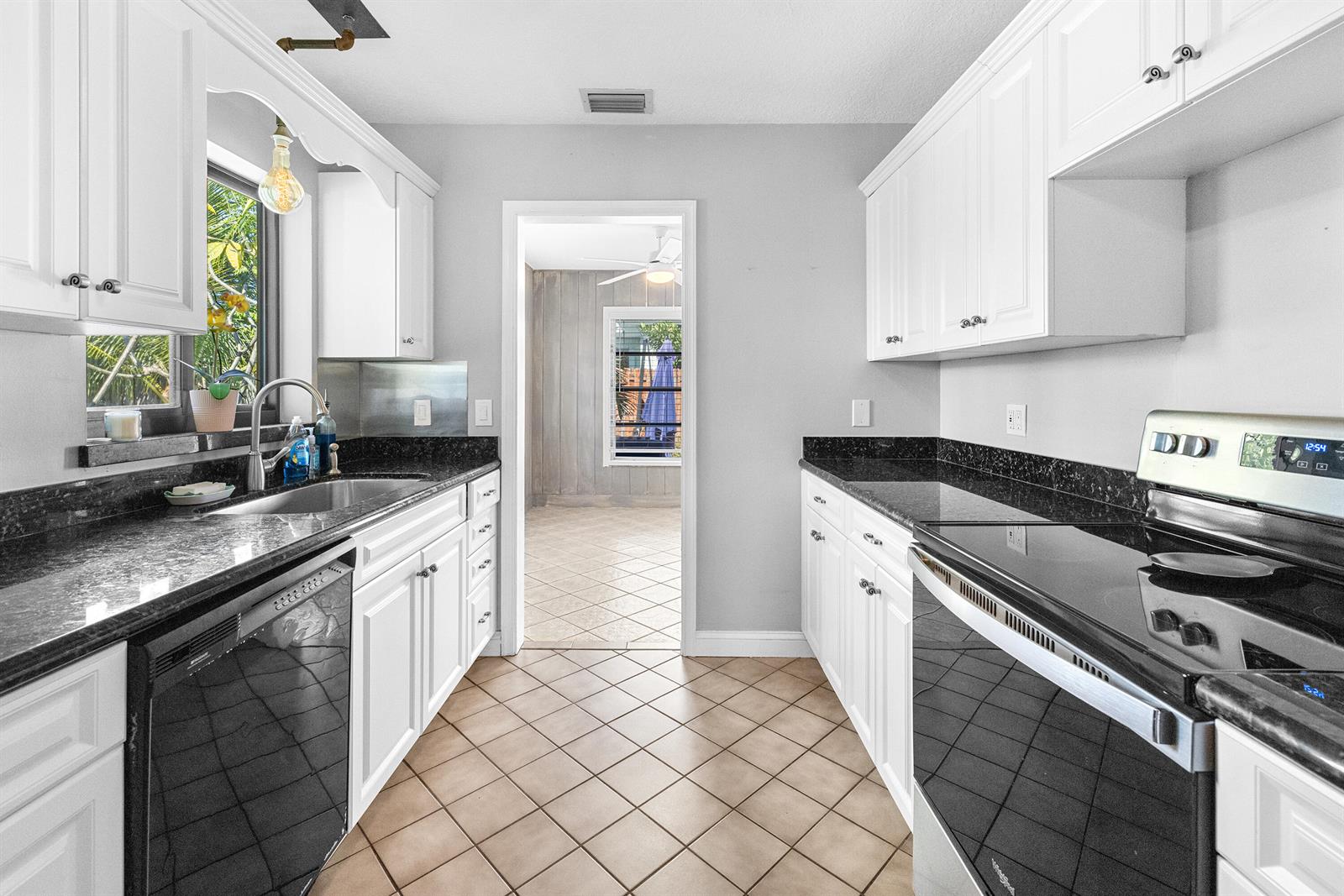 A backyard features a brick house with a blue awning, a fire pit, and palm trees — 815 South Road, Boynton Beach FL 33435, BOYNTON BEACH, FL