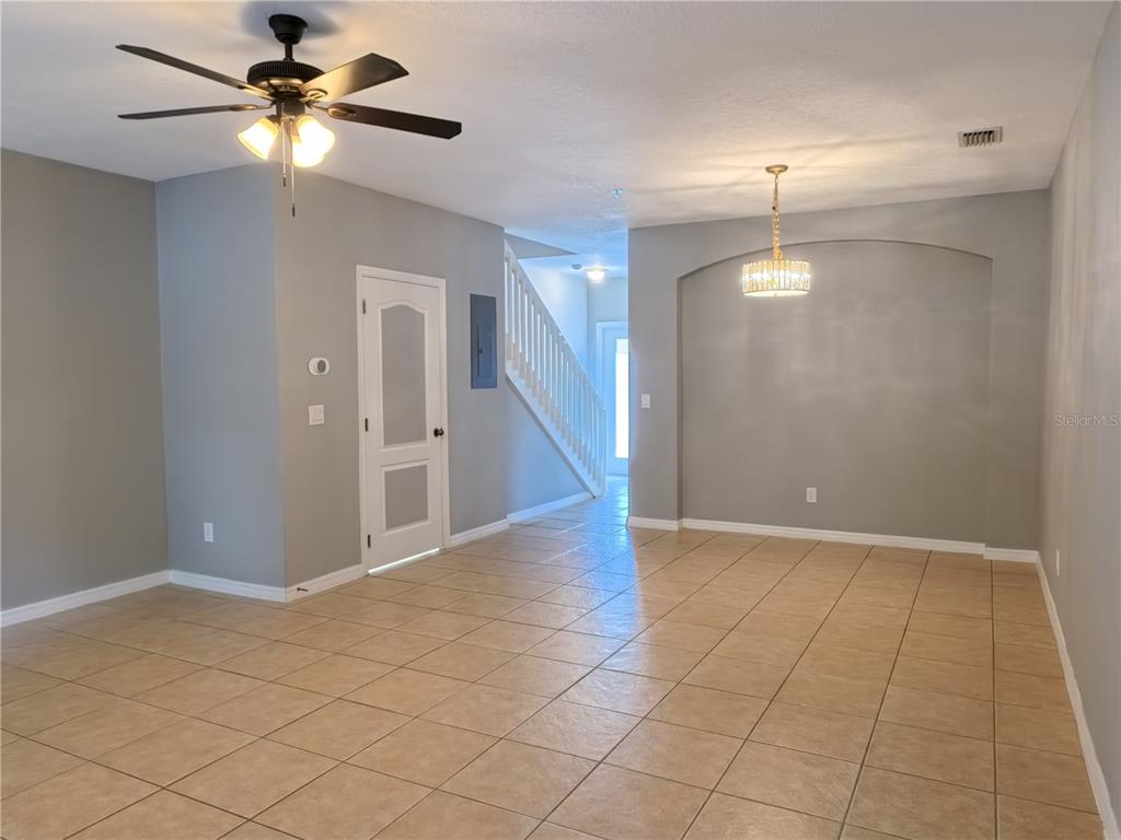 An empty room features beige tile flooring, a ceiling fan, and a recessed dining area — 13349 HARBOR SHORE LANE, WINTER GARDEN, FL