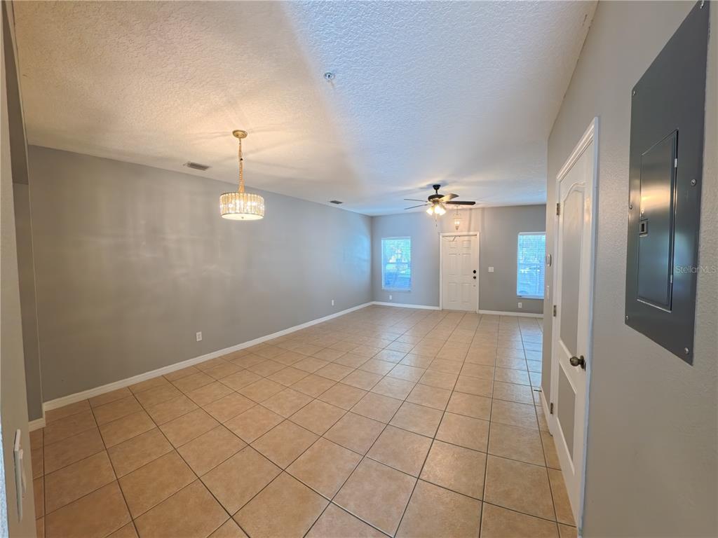 An empty room with beige tile flooring, gray walls, a chandelier, and a ceiling fan — 13349 HARBOR SHORE LANE, WINTER GARDEN, FL