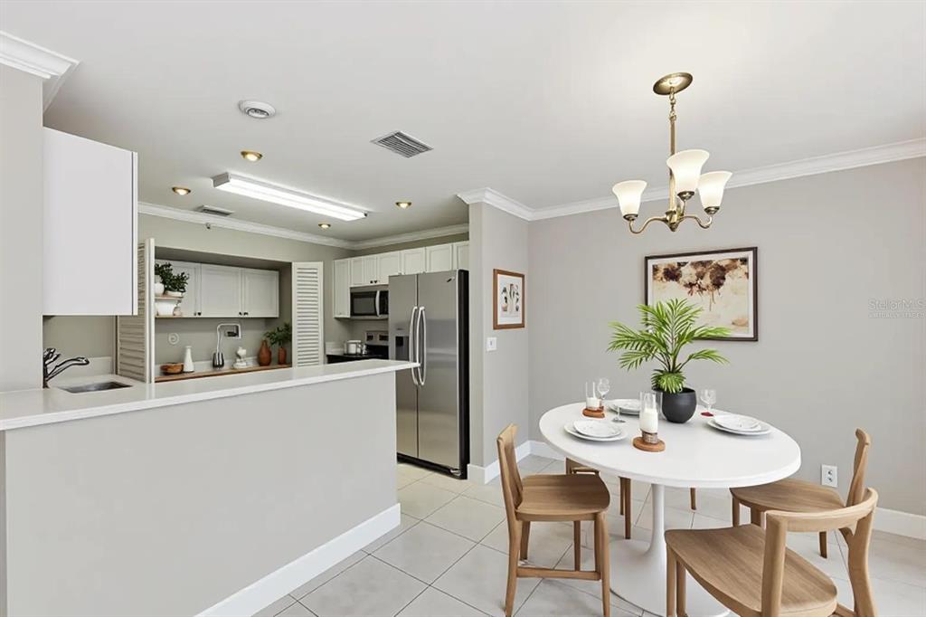 A kitchen with white cabinets and stainless steel appliances opens to a dining area — 8741 CLEARY BOULEVARD, FORT LAUDERDALE, FL