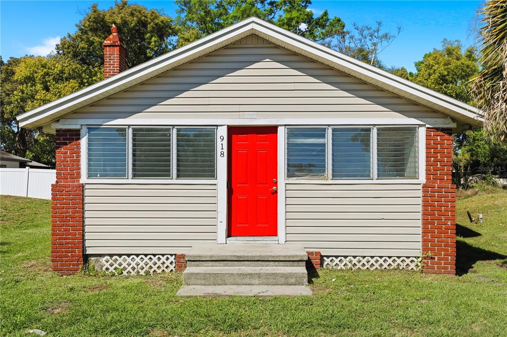 A single-story house with gray siding, a red front door, and a brick chimney — 918 SHOREVIEW DRIVE, ORLANDO, FL